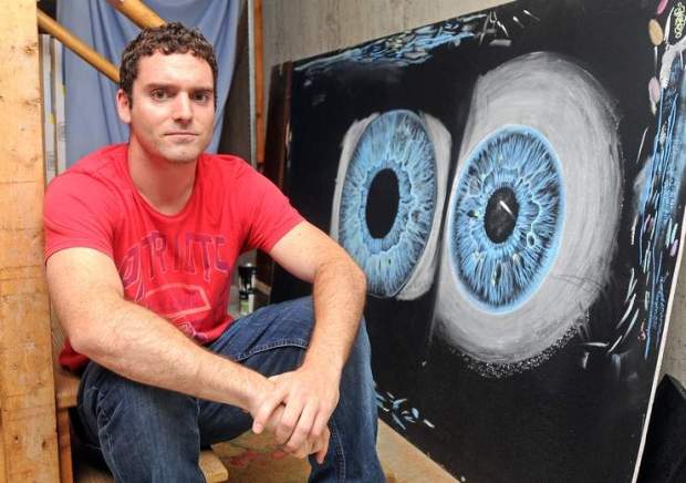 Justin Dowd, a Princeton man who won a contest and will be traveling into outer space next year, sits next to an illustration used in the opening scene of his educational video. (Credit: T&G Staff/STEVE LANAVA)