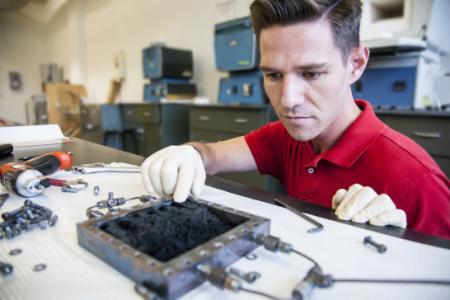 Lt. Will Curtin, a student in the mechanical engineering program, demonstrates the carbon nano-fiber foam (CFF) following its creation in the NPS Functional Materials Laboratory. For the first time, NPS researchers have developed a CFF that behaves as a viscoelastic solid with stable mechanical properties without the need of a polymeric component. (Credit: Javier Chagoya)