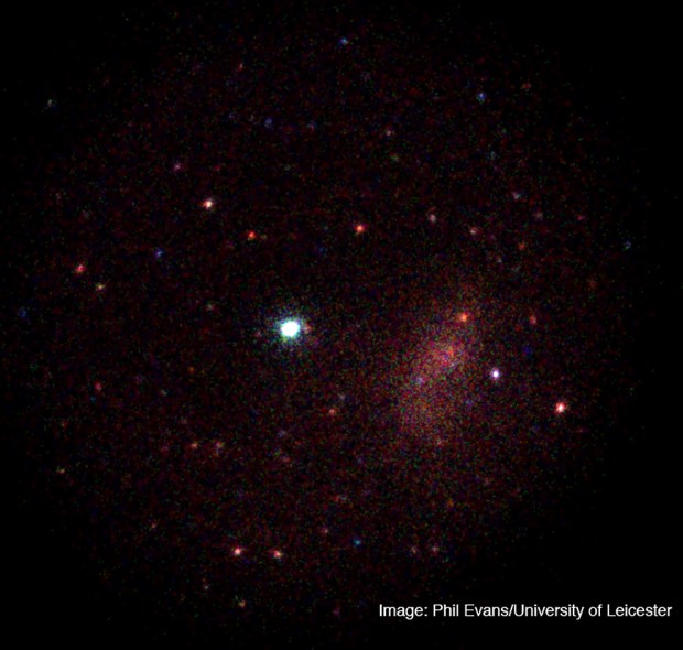 The X-ray image from the Swift X-ray Telescope of the gamma-ray burst GRB 130925. The white object in the center is the gamma-ray burst.  The large diffuse region to the right is a cluster of galaxies. The other objects are X-ray-emitting celestial objects, most likely supermassive black holes at the centers of distant galaxies. The full image is approximately the size of the full moon. (Credit: Phil Evans/ University of Leicester)