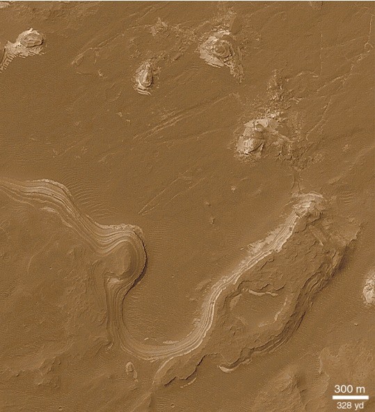 “Colorized” subframe of Mars Orbiter Camera image M03-02733 of layered deposits inside Holden Crater. Because a large valley called Uzboi Vallis can be seen entering into the crater, the layers shown here could be from the deposition of sediments in the water from this valley. Illumination from the upper left. Figure courtesy of Malin Space Science Systems/NASA. 